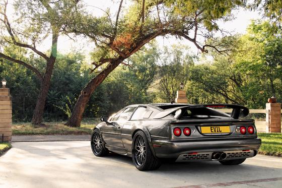 AI-generated preview of a dark grey 2000 Lotus Esprit V8, rear left view, on Splux SD-12 wheels